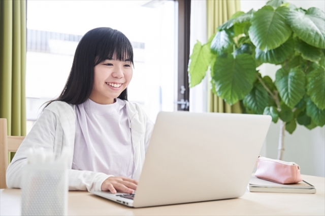 a middle school girl with a laptop smiling in a bright living room, having a conversation online